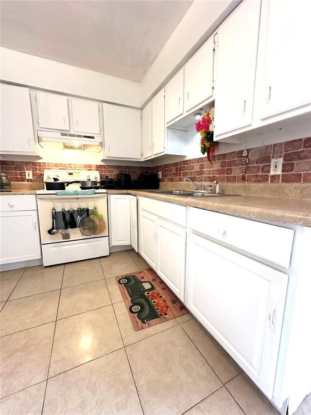 kitchen with light tile patterned floors, sink, decorative backsplash, white electric stove, and white cabinets