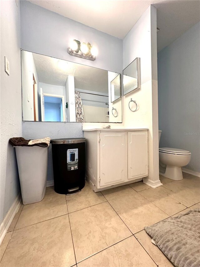 bathroom with tile patterned flooring, toilet, walk in shower, and vanity