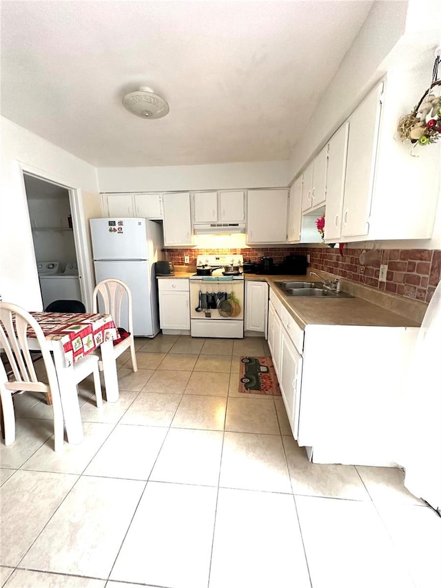 kitchen with white appliances, light tile patterned floors, washer / dryer, sink, and white cabinetry