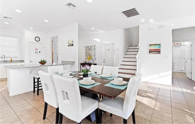 dining space with light tile patterned floors, visible vents, and stairs