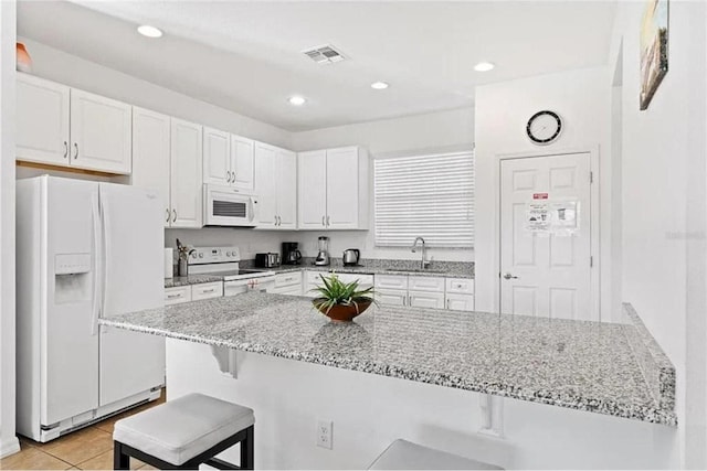 kitchen featuring visible vents, white appliances, white cabinetry, and a sink