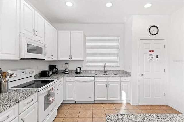 kitchen featuring light tile patterned floors, white appliances, white cabinetry, and a sink