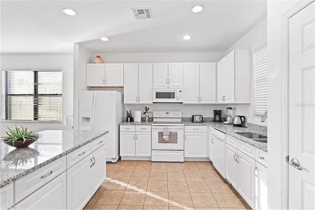 kitchen featuring white appliances, visible vents, recessed lighting, a sink, and white cabinets