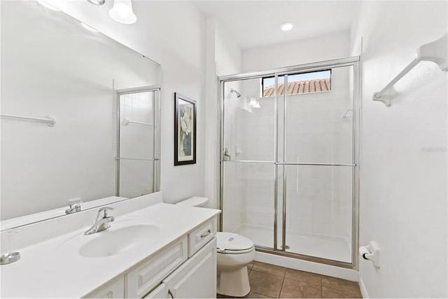 bathroom featuring tile patterned flooring, a shower stall, toilet, and vanity