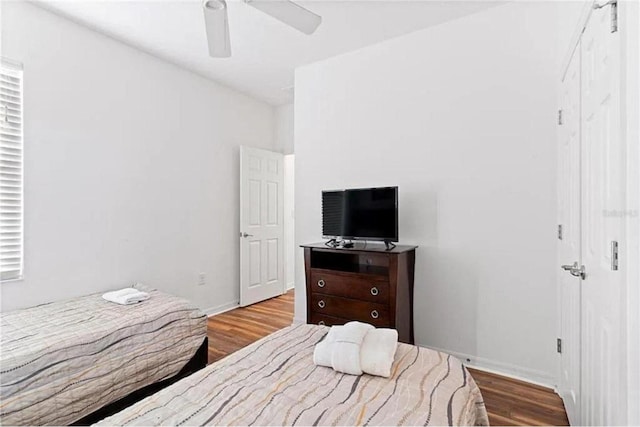 bedroom with a ceiling fan, wood finished floors, and baseboards