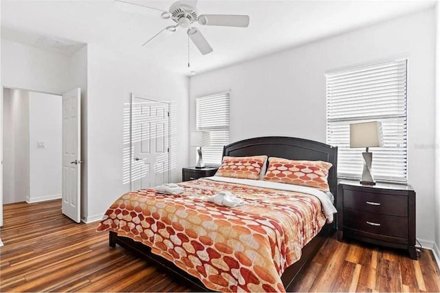 bedroom with a closet, baseboards, wood finished floors, and a ceiling fan