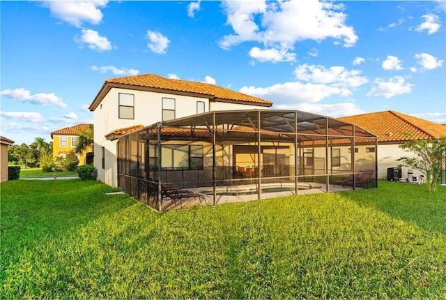 back of house featuring glass enclosure, a patio, stucco siding, a tiled roof, and a lawn