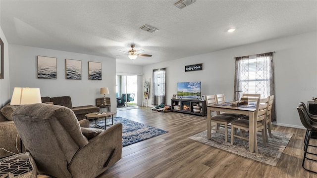 living room with a textured ceiling, wood-type flooring, and ceiling fan