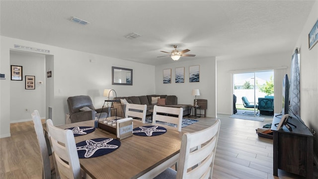 dining area featuring ceiling fan, a textured ceiling, and light wood-type flooring