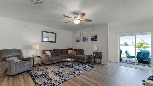 living room featuring a textured ceiling, light hardwood / wood-style floors, and ceiling fan