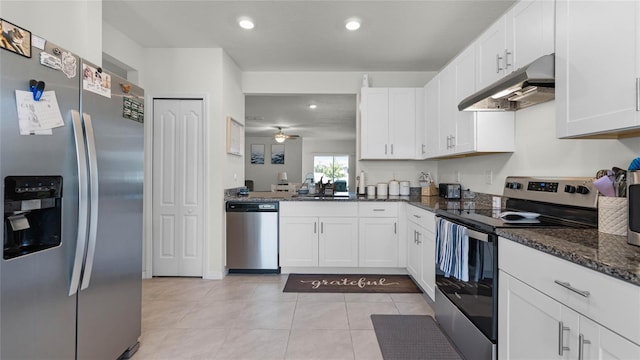 kitchen with appliances with stainless steel finishes, dark stone countertops, white cabinetry, light tile patterned floors, and sink