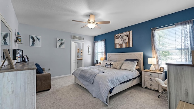 carpeted bedroom with ceiling fan, a textured ceiling, ensuite bathroom, and multiple windows