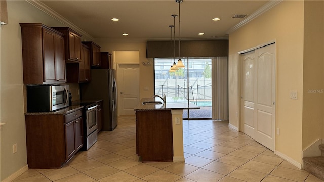 kitchen with ornamental molding, a center island with sink, dark stone counters, appliances with stainless steel finishes, and decorative light fixtures