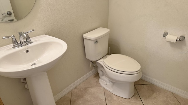 bathroom with toilet, sink, and tile patterned floors