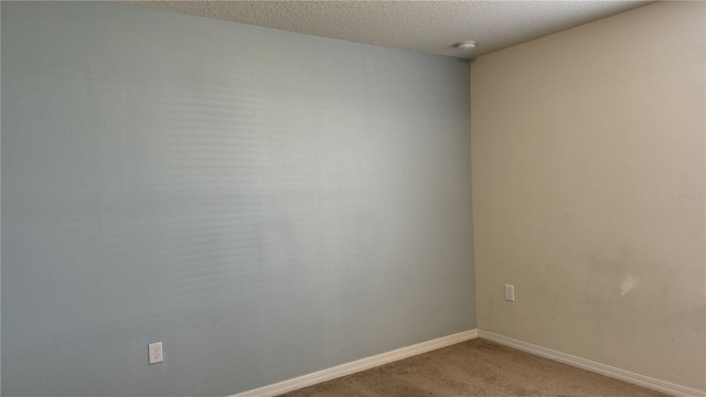 carpeted empty room featuring a textured ceiling