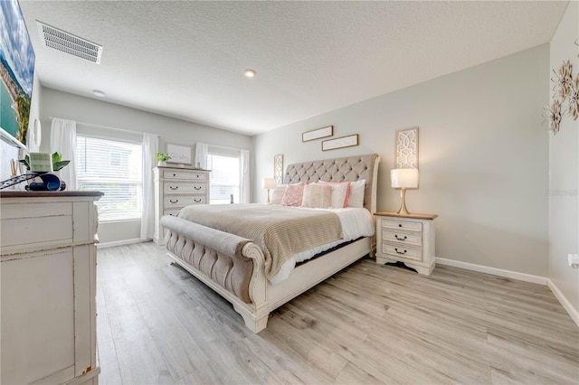 bedroom featuring a textured ceiling and light hardwood / wood-style floors