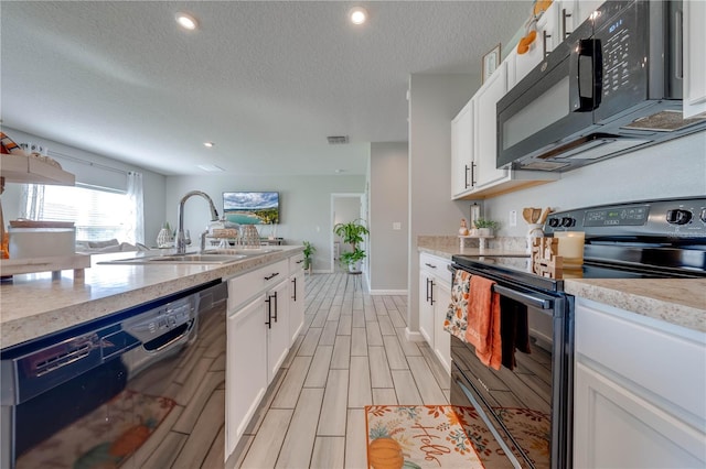 kitchen with a textured ceiling, light stone countertops, black appliances, sink, and white cabinets