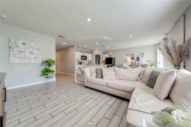 living room with a textured ceiling and light hardwood / wood-style flooring