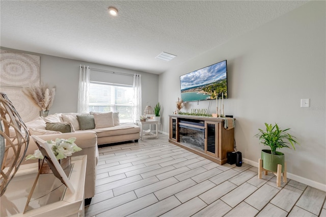 living room featuring light wood-type flooring and a textured ceiling