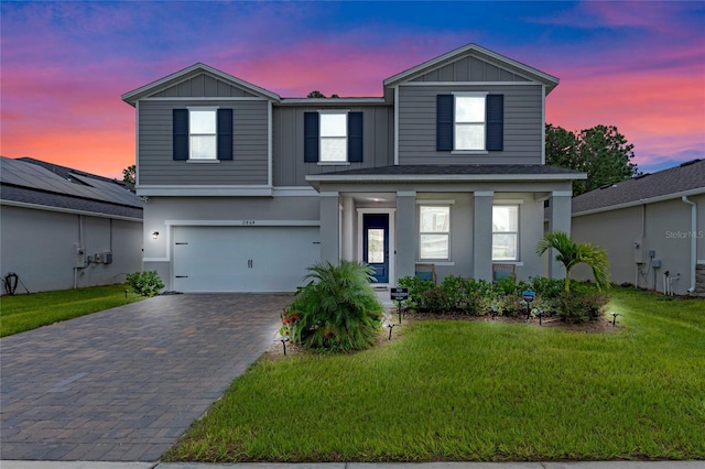 view of front of house with covered porch, a lawn, and a garage