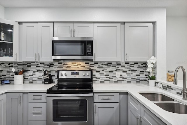 kitchen featuring gray cabinets, stainless steel appliances, tasteful backsplash, and sink