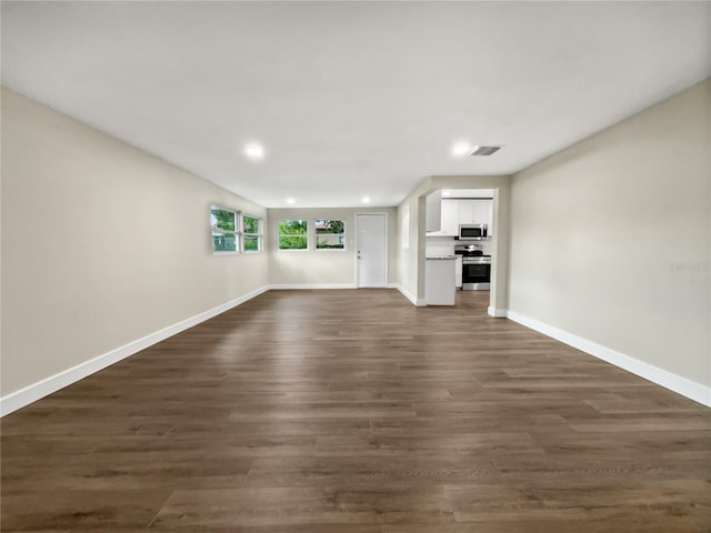 unfurnished living room with dark wood-style floors, visible vents, baseboards, and recessed lighting