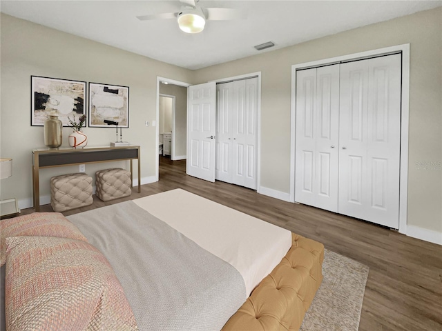 bedroom with ceiling fan, dark hardwood / wood-style floors, and multiple closets