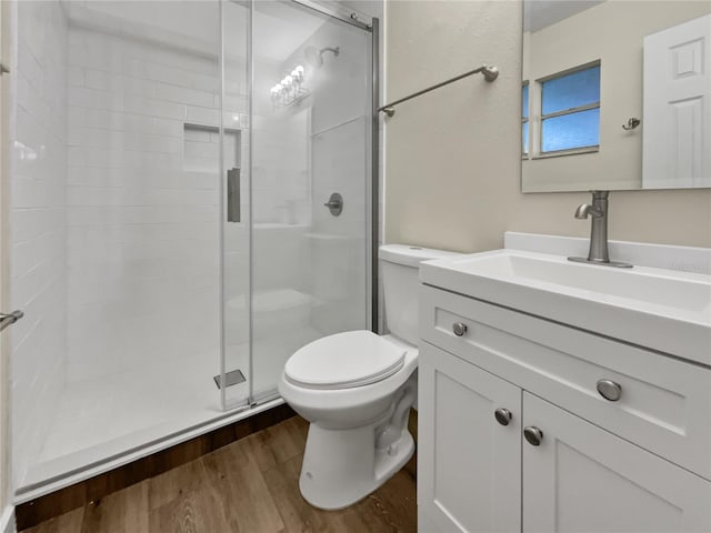 bathroom with wood-type flooring, toilet, a shower with door, and vanity