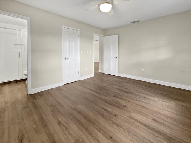 unfurnished bedroom with ceiling fan, dark hardwood / wood-style floors, and ensuite bath