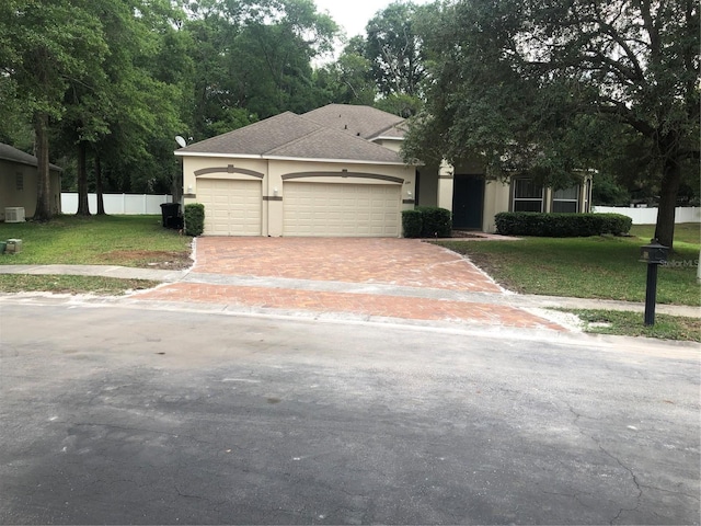 view of front facade featuring a garage, driveway, fence, a front lawn, and stucco siding