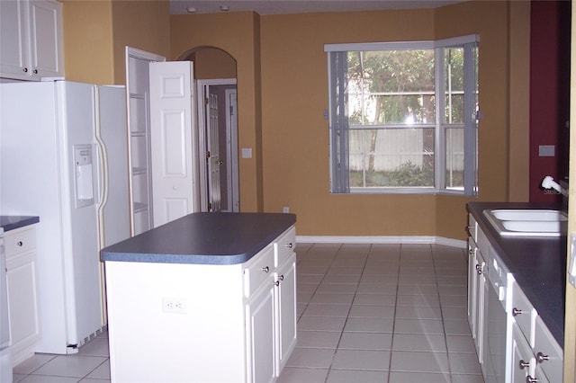 kitchen featuring white fridge with ice dispenser, dark countertops, a sink, and plenty of natural light