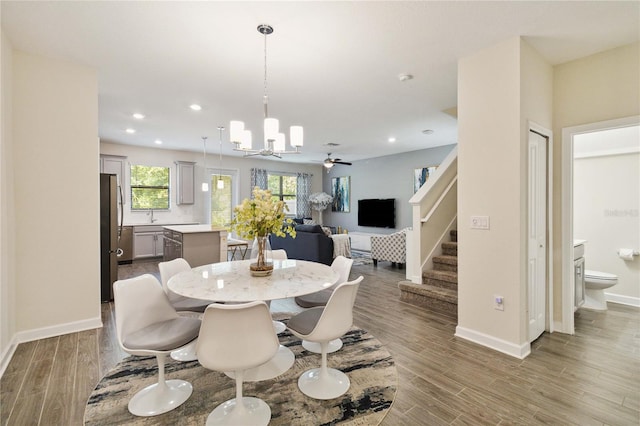 dining area with ceiling fan with notable chandelier and hardwood / wood-style floors