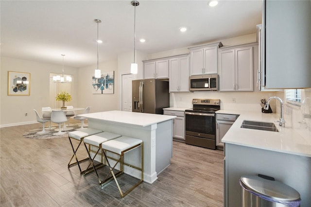 kitchen with appliances with stainless steel finishes, a center island, sink, and decorative light fixtures