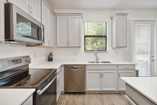 kitchen with backsplash, light hardwood / wood-style floors, sink, and stainless steel appliances