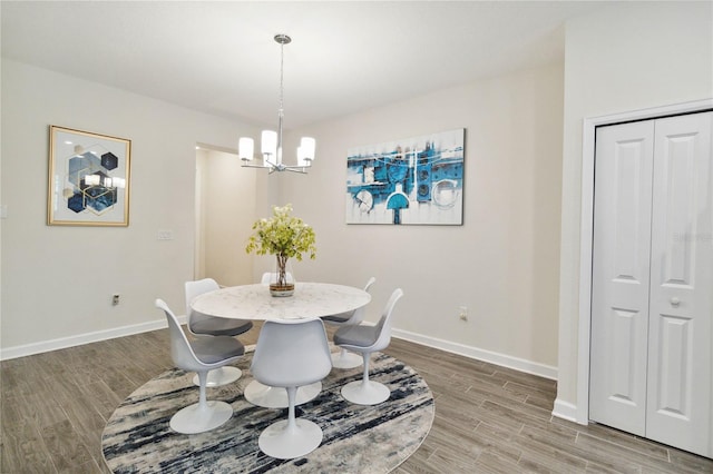 dining space featuring wood-type flooring and an inviting chandelier