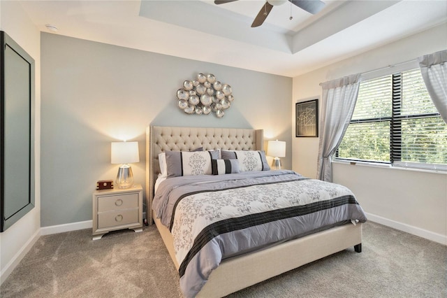 carpeted bedroom with ceiling fan and a tray ceiling