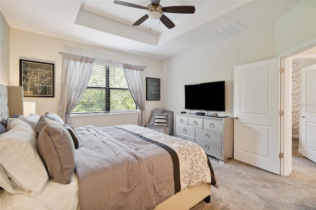 carpeted bedroom featuring a raised ceiling and ceiling fan