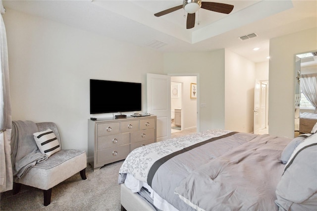 carpeted bedroom with ceiling fan, a raised ceiling, and ensuite bathroom