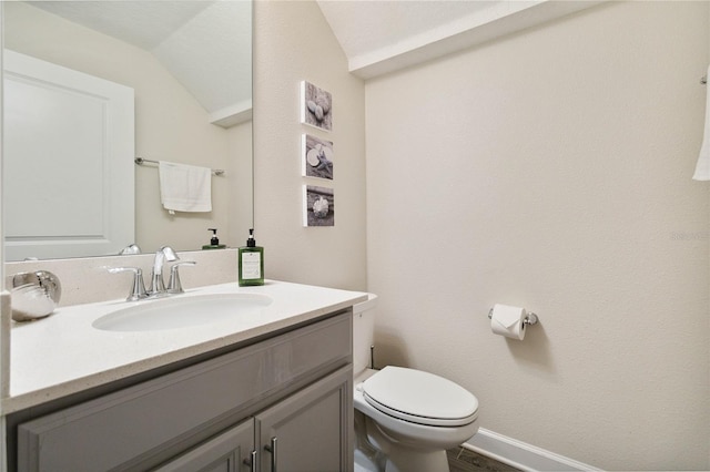 bathroom with vaulted ceiling, vanity, and toilet