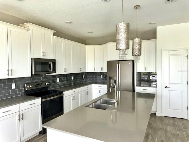 kitchen with backsplash, a kitchen island with sink, dark wood-type flooring, stainless steel appliances, and sink