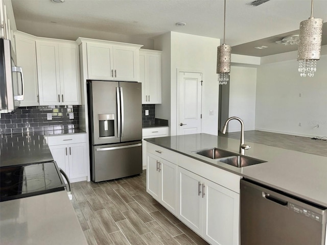 kitchen with backsplash, appliances with stainless steel finishes, light hardwood / wood-style floors, sink, and white cabinetry