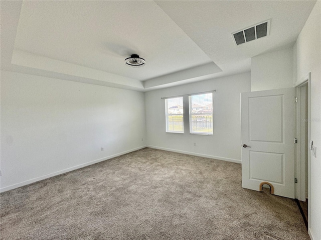 carpeted spare room featuring a tray ceiling