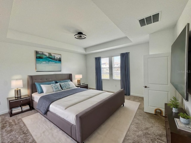 bedroom with light colored carpet and a raised ceiling