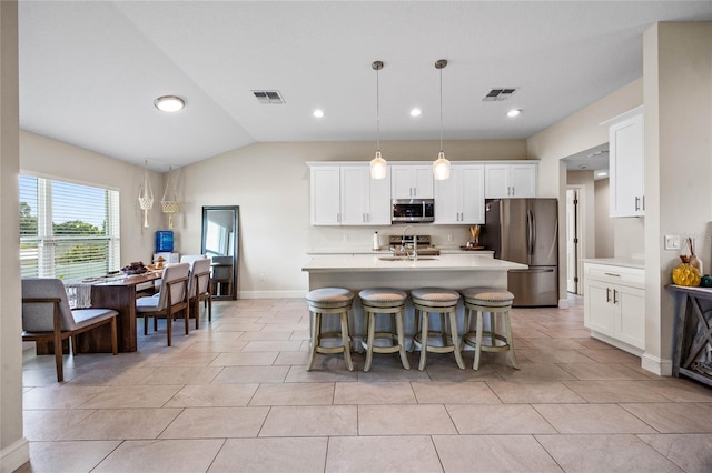 kitchen featuring stainless steel appliances, decorative light fixtures, a center island with sink, white cabinetry, and lofted ceiling