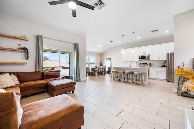 tiled living room with ceiling fan, lofted ceiling, and sink