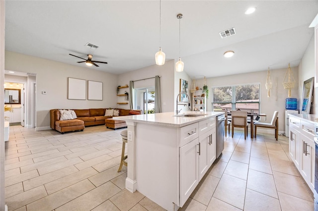 kitchen featuring sink, a center island with sink, dishwasher, white cabinetry, and hanging light fixtures