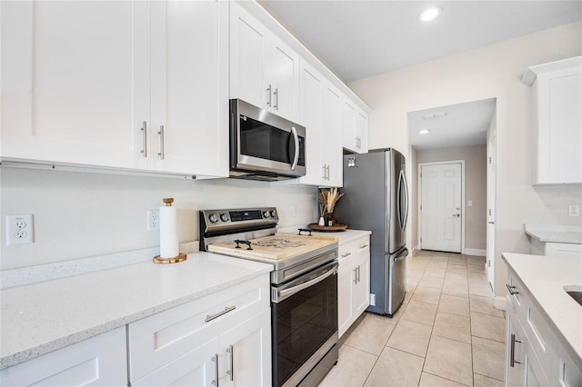 kitchen featuring light tile patterned floors, stainless steel appliances, white cabinetry, and light stone counters