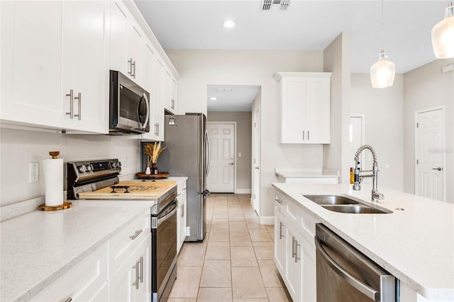 kitchen featuring white cabinets, sink, light tile patterned floors, appliances with stainless steel finishes, and decorative light fixtures