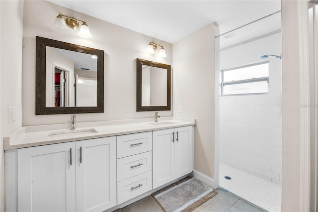 bathroom with tile patterned flooring, a tile shower, and vanity