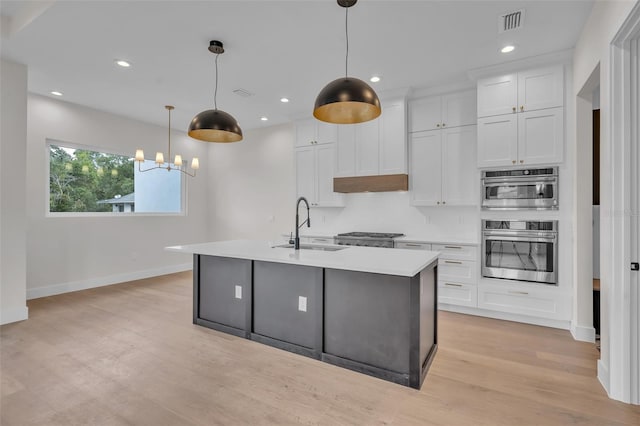 kitchen with light wood-type flooring, sink, pendant lighting, and white cabinets